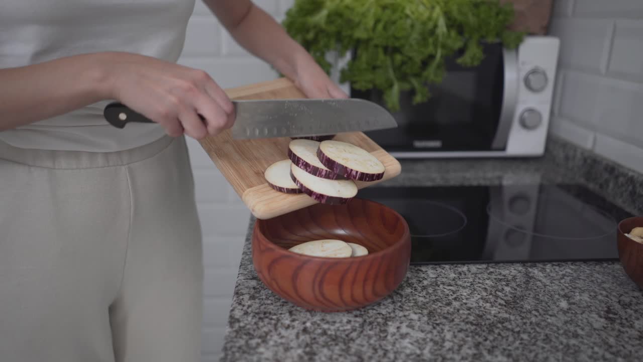 Woman Chopping Eggplant in Kitchen