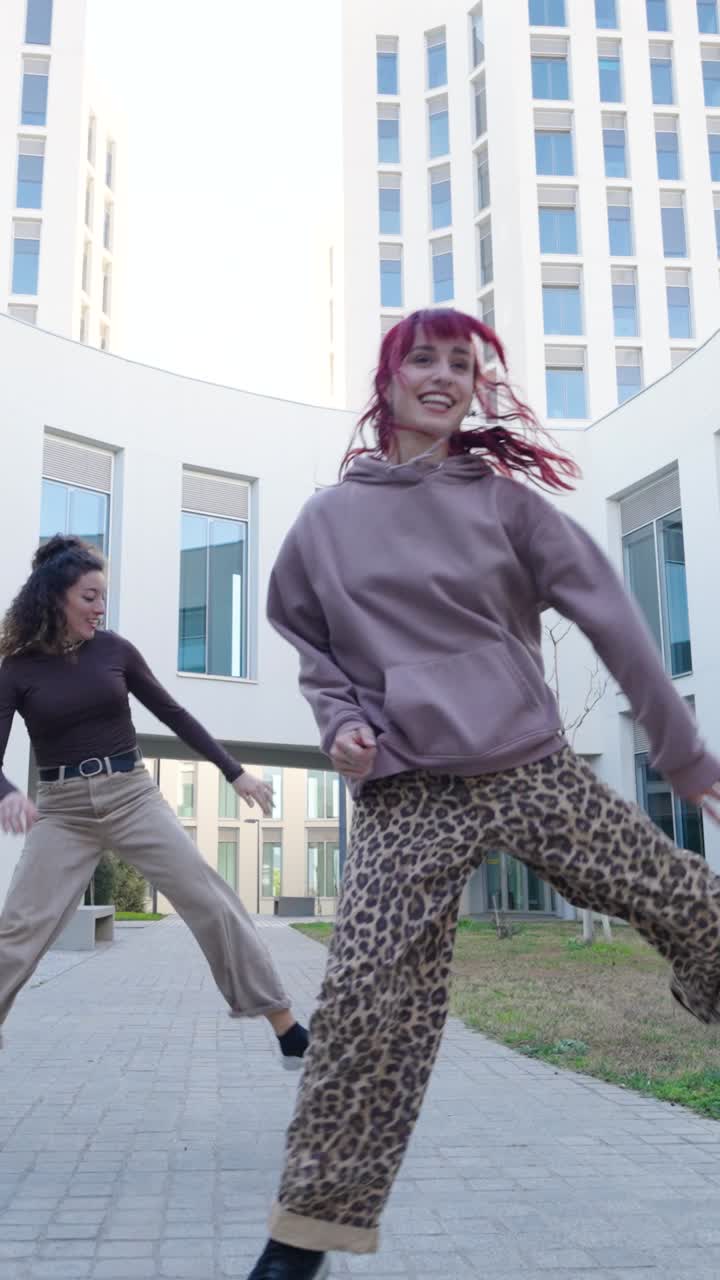 Young women dancing outside modern building
