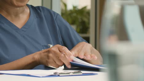 Mid-Section-Female-Middle-Aged-Doctor-Looking-at-Notes