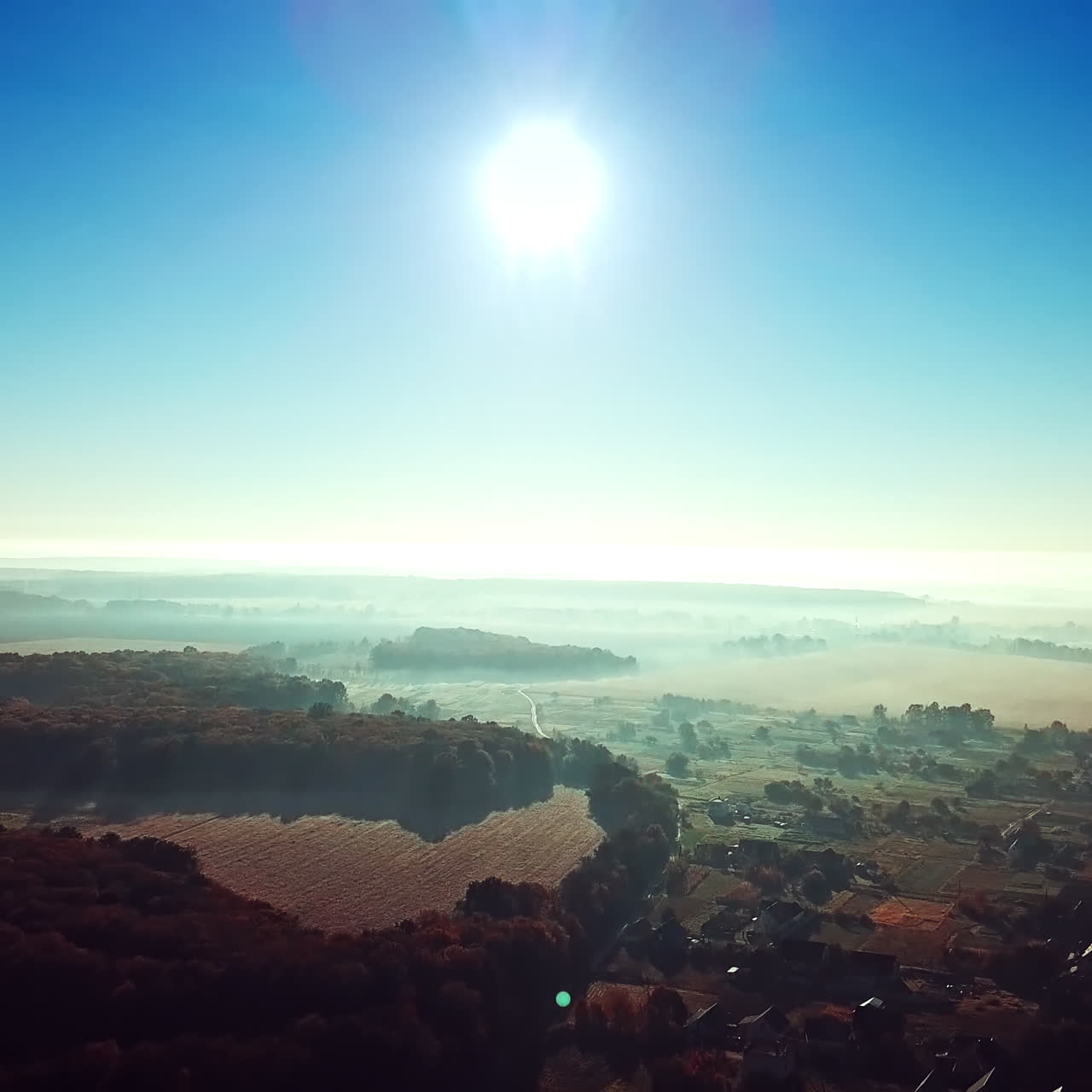 Morning sunrise in the village on misty weather. Panoramic view of beautiful dawn over the roofs of the houses and big forest. Aerial View. Soft sun light. Slow motion.