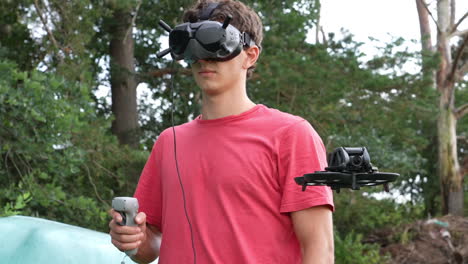 young man controlling fpv drone with motion remote controller and goggles headset