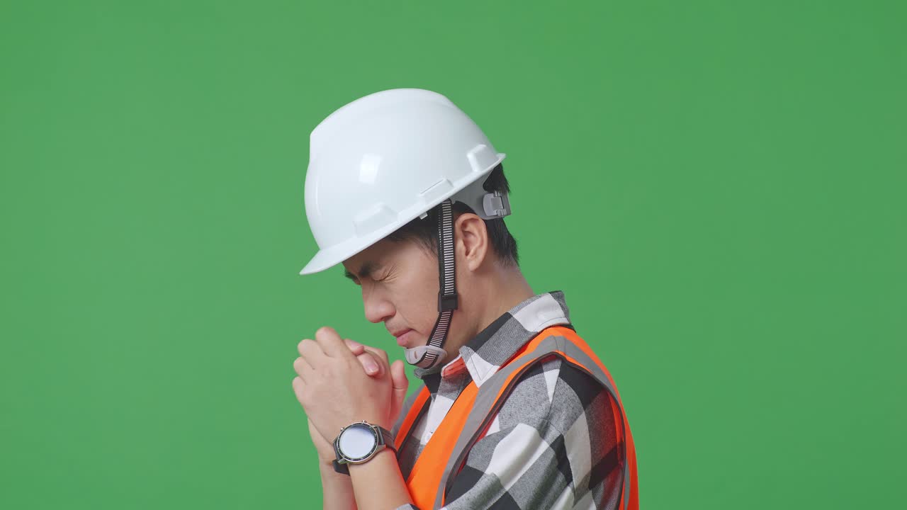 Close Up Side View Of Asian Male Engineer With Safety Helmet Pray For Something While Standing In The Green Screen Background Studio
