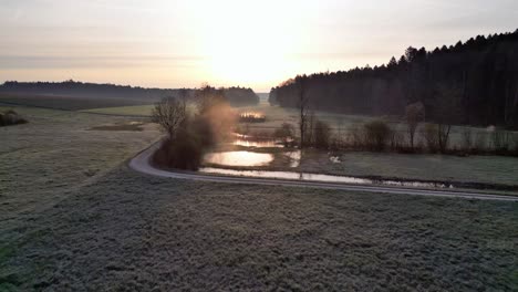 Droneflight-in-the-Sunrise-over-rural-switzerland-nature-reserve-area-with-little-lakes-and-creeks-and-forest