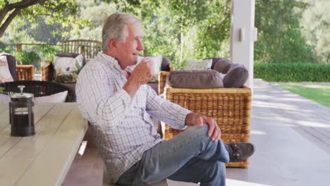 Senior-Caucasian-man-spending-time-and-drinking-a-beverage-in-the-garden