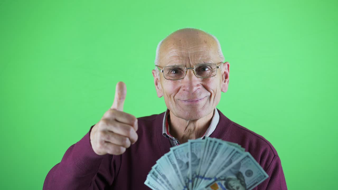 미소로 미국 달러의 팬을 보여주는 안경을 입은 행복한 노인