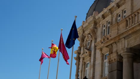 the palacio consistorial stands proudly with spanish flags waving in the air, accentuating the building’s historic charm and symbolizing national pride against a majestic backdrop.
