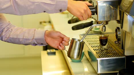 Mid-section-of-waiter-making-espresso