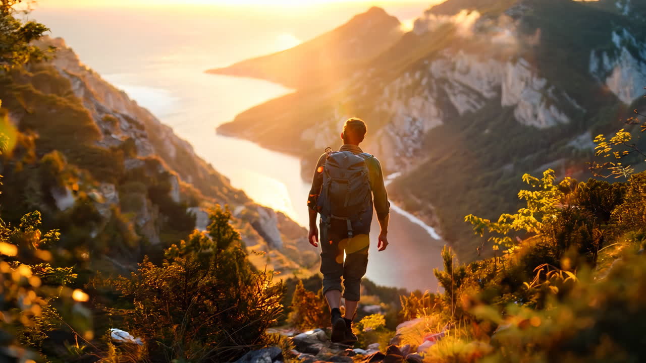 Sunset Hiker Exploring Scenic Mountain Trails in Autumn. A lone hiker journeys along a mountain path, surrounded by lush greenery, as the sun sets over a serene river valley.