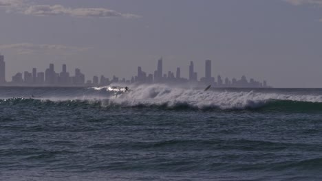 powerful ocean waves with adventurous surfers at currumbin alley beach. surfers paradise cityscape in background. wide shot