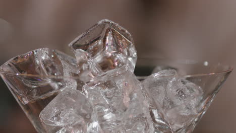 detailed close-up of a martini glass filled with ice cubes next to a glass of whiskey, ideal for representing the art of mixology, premium drinks.