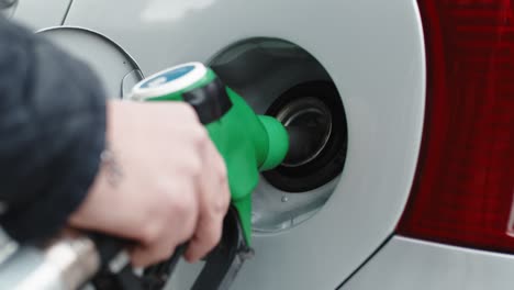 hand of a gas station man is putting gasoline into a car