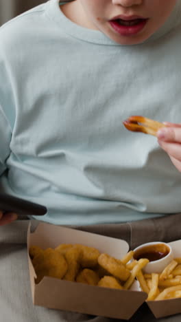a person eating fast food, including french fries and chicken nuggets with dipping sauce