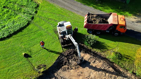 excavator and dump truck moving soil at construction site