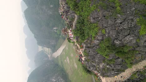 vertical - tourists enjoying scenery at hang mua viewpoint in ninh binh, vietnam. orbiting drone shot