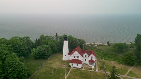 aerial orbit of point iriquois lighthouse with wildfire smoke, lake superior, michigan