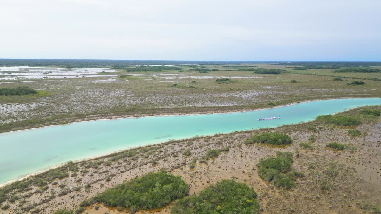 Aerial view over coastal wetlands and bright turquoise channels near Bacalar, Quintana Roo, Mexico, showcasing wild vegetation, shallow water patterns, and natural shoreline textures