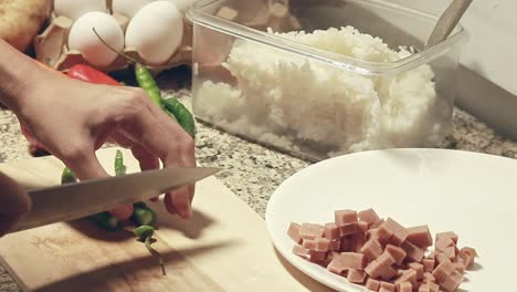Candid cooking scene of chopping green chilies in a kitchen counter surrounded by different ingredients that shows a genuine moment of daily domestic home life