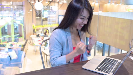 Exitosa-Mujer-Asiática-Trabajadora-De-Cabello-Largo-Feliz-Gritando-Frente-A-La-Computadora-Portátil-En-El-Lugar-De-Trabajo-De-La-Oficina