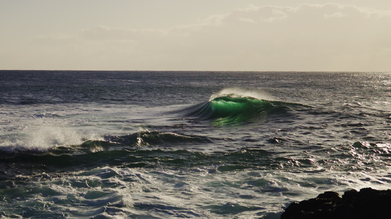 Turbulent water flows under cloudy sunset light, textured sea surface ripples in golden hour