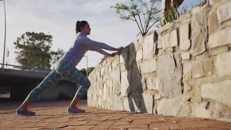 caucasian woman stretching against a wall