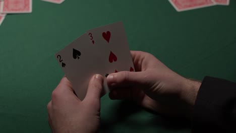 gambler draws two cards and puts them back in a dark moody casino