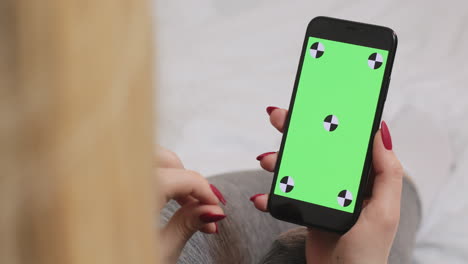 mujer sosteniendo un teléfono inteligente con una pantalla verde