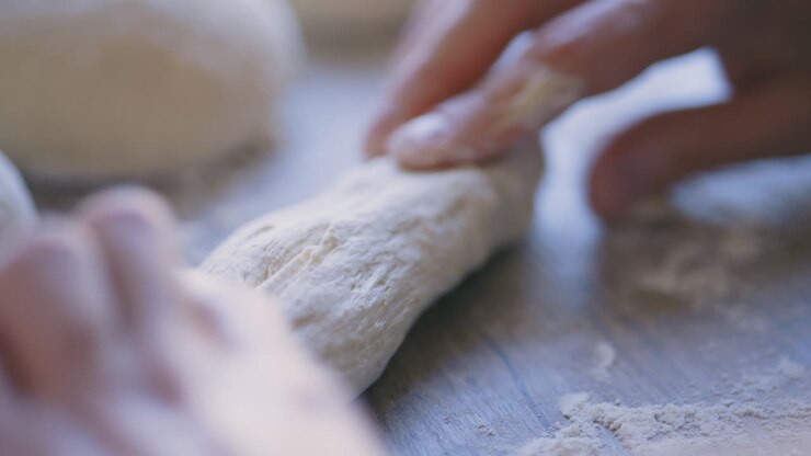 Close-up of young white male hands kneading dough on wooden table