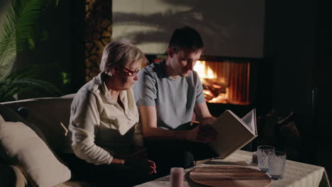 grandmother and grandson reading together by the fireplace