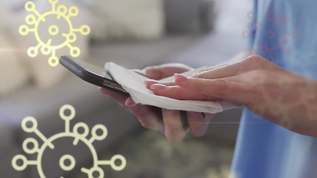 animación de las células del virus covid 19 sobre una mujer caucásica desinfectando un teléfono inteligente