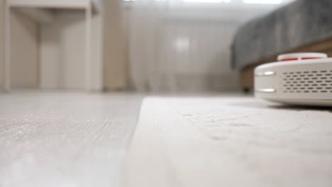 white robot vacuum cleaner hoovers floor driving to carpet