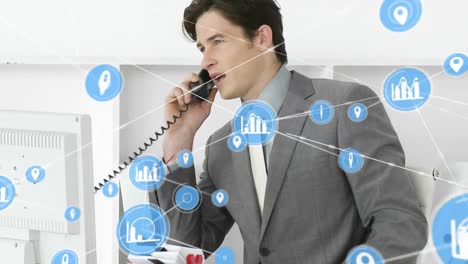 animation of network of digital icons against caucasian businessman talking on telephone at office