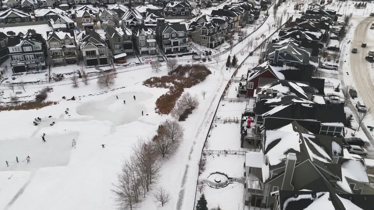 아이들이 하키를 하고 있는 에어드리 앨버타의 쿠퍼스 동네에 있는 커뮤니티 연못의 공중 드론 비행