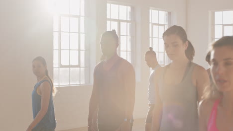 yoga-class-of-young-healthy-people-practicing-warrior-pose-enjoying-fitness-lifestyle-exercising-in-studio-at-sunrise