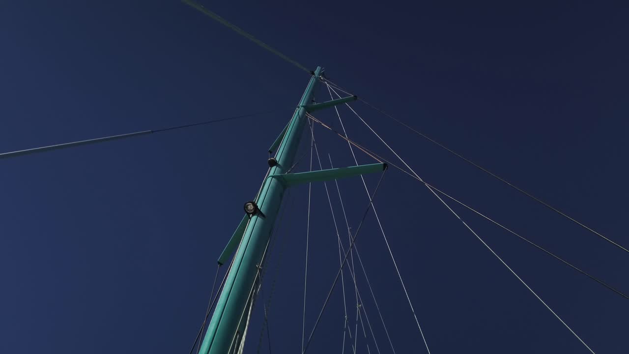 메인 돛을 내리고 많은 줄이 맨 위로 향하는 쌍동선의 돛대 아래에서 발사