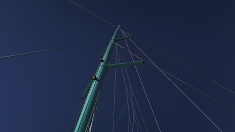 una toma desde debajo del mástil de un catamarán con la vela principal bajada y muchas cuerdas subiendo a la cima