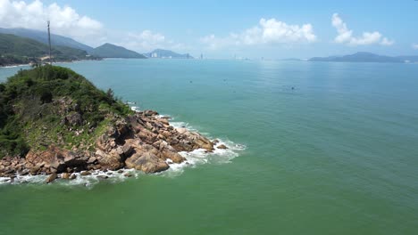drone flying over beautiful rocky island at bai xep beach with quy nhon skyline in distance