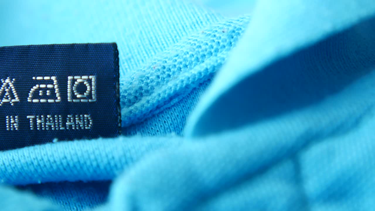 세탁 지침과 '태국에서 제조된' 텍스트가 담긴 파란색 관리 라벨의 클로즈업