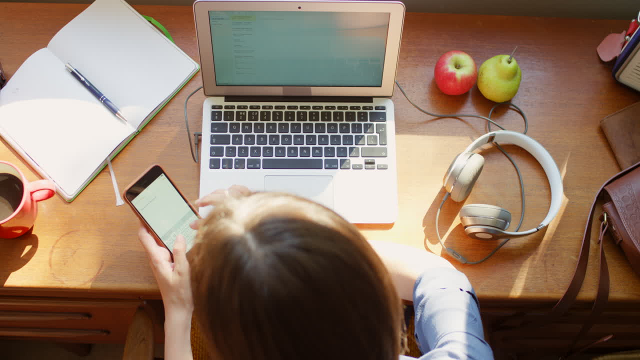 estudiante trabajando desde casa en portátil y teléfono