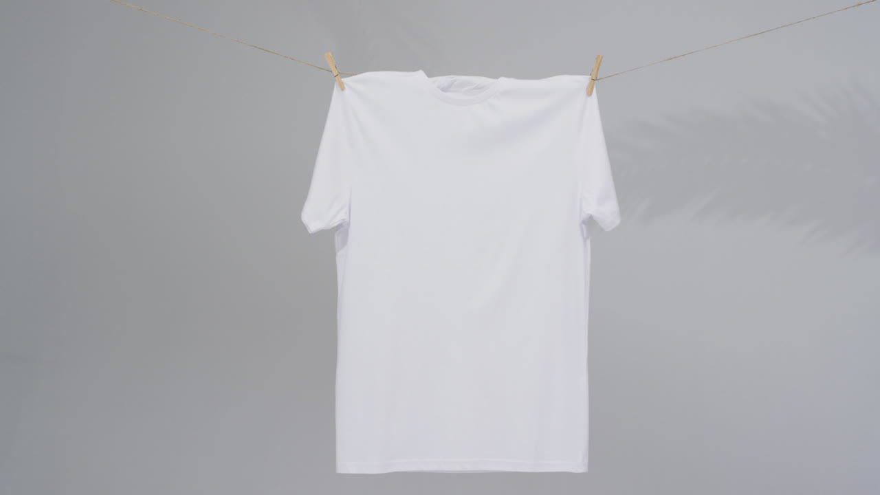 Video of white t shirt with clothes pegs and copy space on grey background