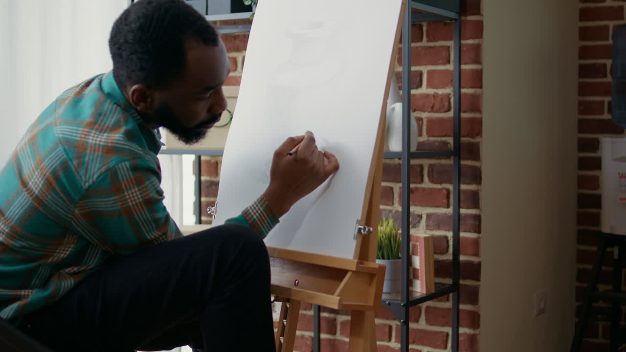 Creative man trying to draw vase model on canvas at art lesson