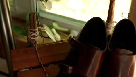 gorgeous flat lay of a grooms shoes and tie in a well lit room filled with wood detail and plants