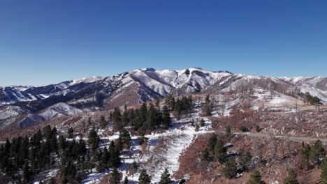 Drone-shot-pushing-forward-revealing-a-snow-covered-mountain-with-trees