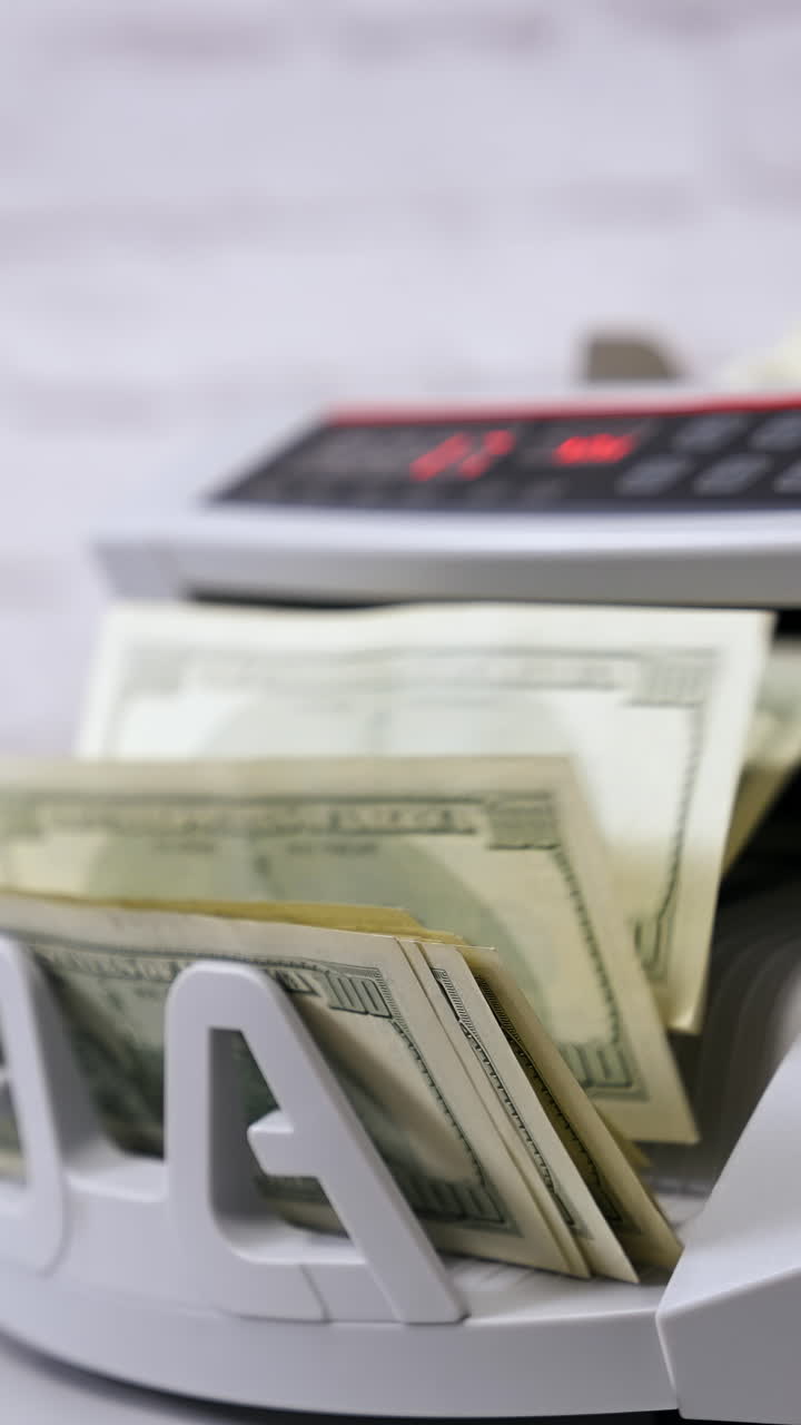 Macchina contabanconote elettronica. Macchina contabanconote con banconote da 100 dollari USA. Attrezzatura bancaria automatica per il conteggio del denaro contante. Video verticale.