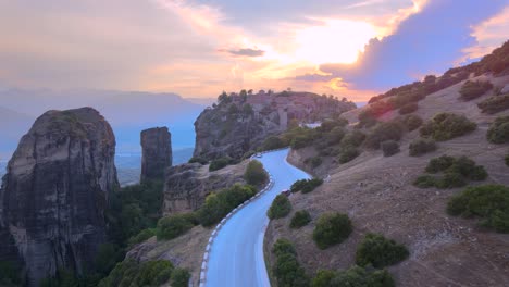 Coche-Acercándose-A-Los-Monasterios-De-Meteora-Durante-La-Puesta-De-Sol,-Antena,-Grecia