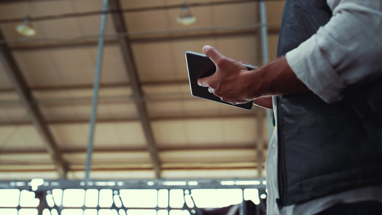 유제품 매니저 가 혼자 가축 창고 에서 일 하고 있다. 노동자 손 이 패드 를 들고 있는 컴퓨터 클로즈업