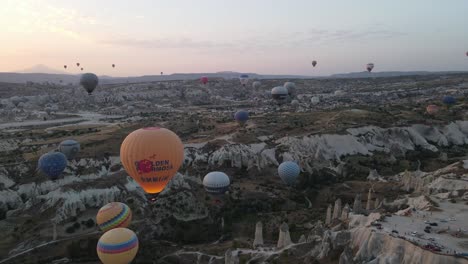 drone view of dozens of tourist balloons flying in the valley near sunrise, turkey cappadocia