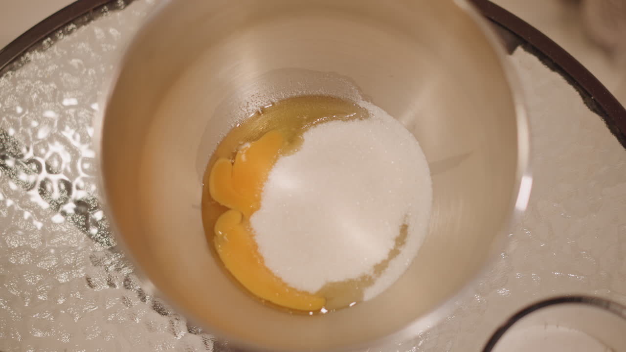 Closeup eggs and sugar in bowl, metallic mixing basin, granulated sugar piled over yolks, soft warm lighting, rustic countertop, cozy autumn baking mood, slow patient prep for pie filling