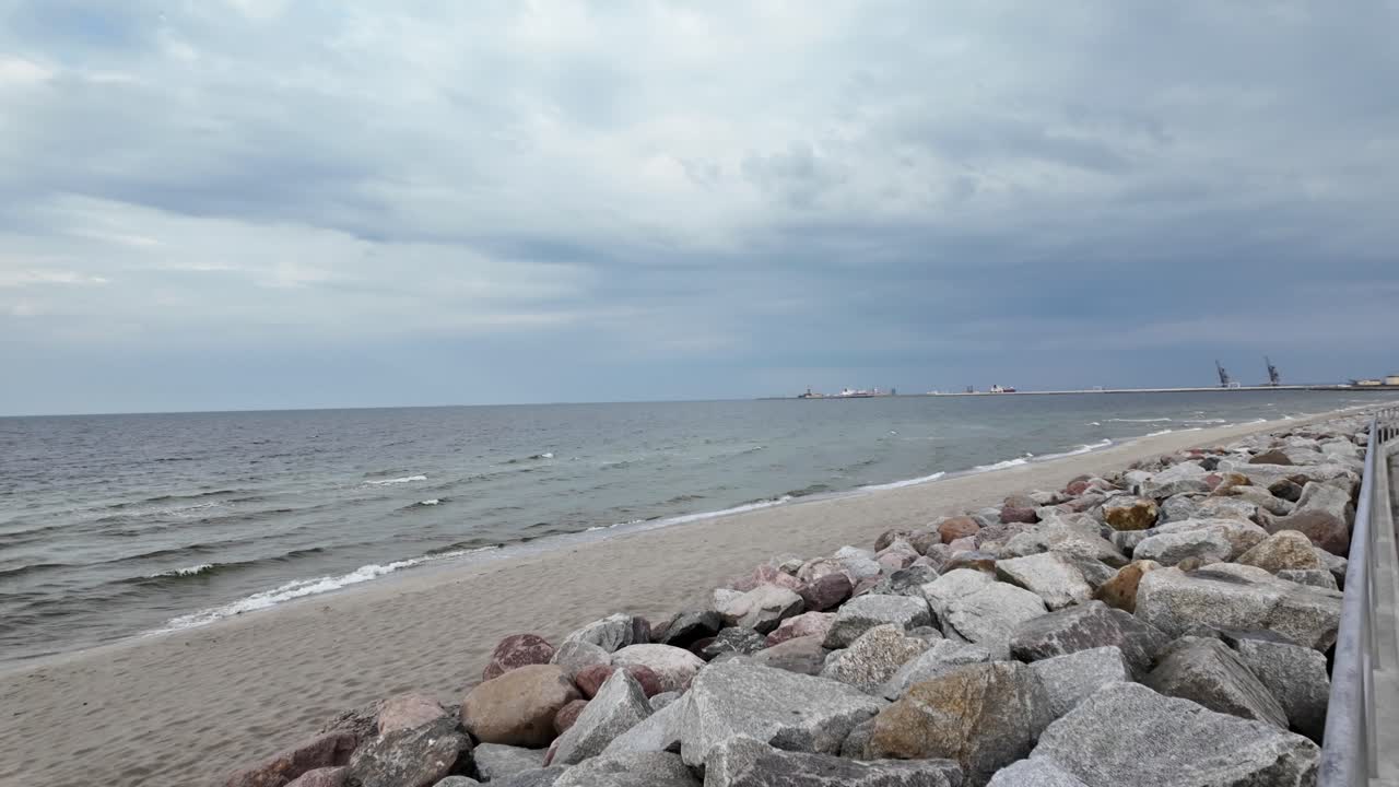 폭풍이 불어오는 웨이처에서 돌로 된 방파제를 가진 모래 해변