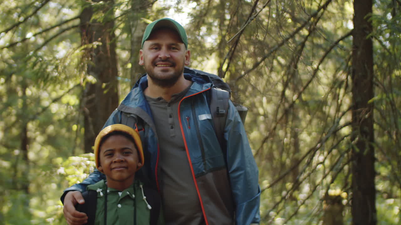 retrato de padre positivo y hijo pequeño en el bosque