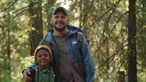 portrait of positive father and little son in woods